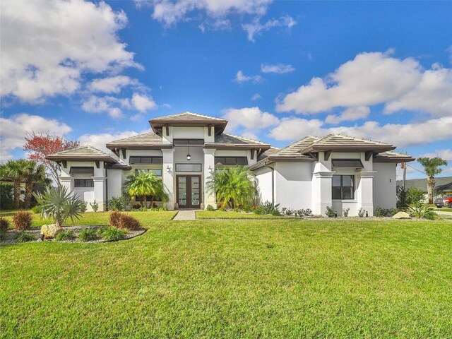 prairie-style home featuring french doors, a front lawn, and stucco siding