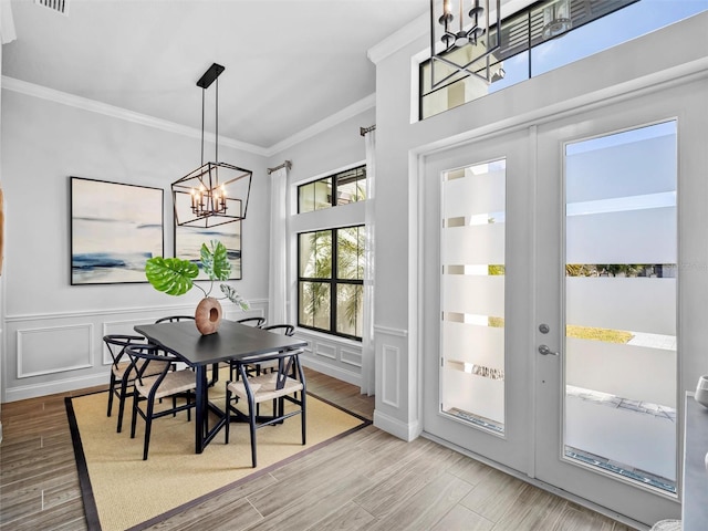 dining space featuring ornamental molding, wood finished floors, french doors, a chandelier, and a decorative wall