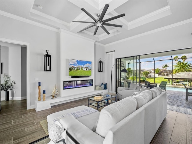 living area featuring coffered ceiling, a glass covered fireplace, a sunroom, ornamental molding, and wood tiled floor