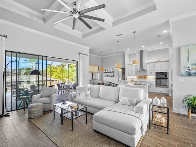 living area with coffered ceiling, wood finished floors, a ceiling fan, visible vents, and crown molding