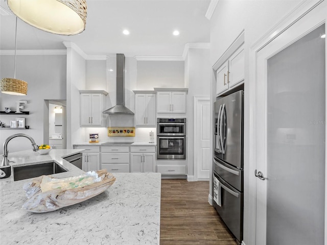 kitchen with stainless steel appliances, wall chimney exhaust hood, a sink, and white cabinetry