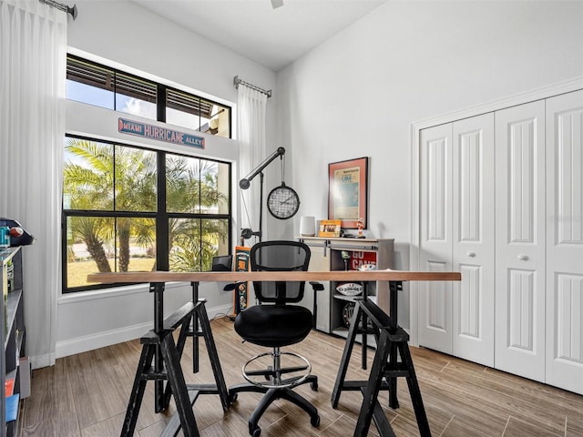 office with a high ceiling, light wood-style flooring, and baseboards