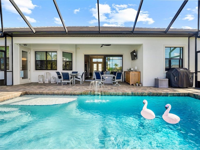 rear view of house with stucco siding, a patio area, ceiling fan, a lanai, and an outdoor pool