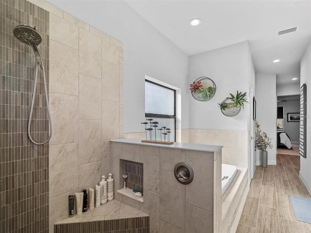 ensuite bathroom with visible vents, ensuite bath, wood finished floors, a garden tub, and walk in shower