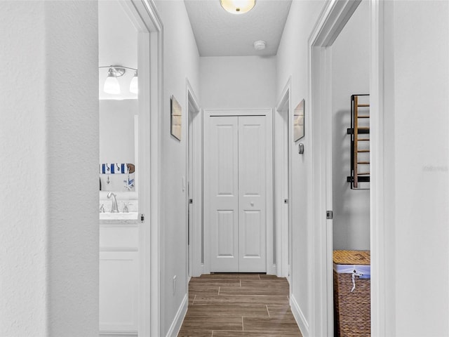 hall featuring baseboards, a textured ceiling, and wood tiled floor