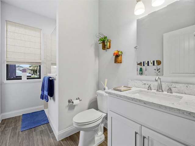 bathroom with baseboards, vanity, toilet, and wood finished floors