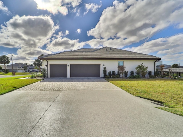 view of front of house with a garage, a tiled roof, decorative driveway, stucco siding, and a front yard