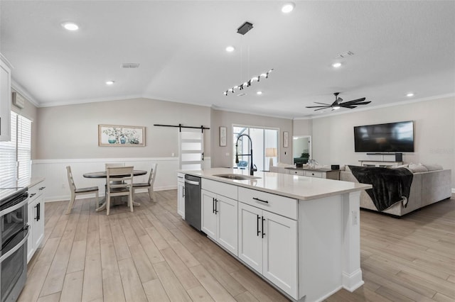 kitchen featuring light wood finished floors, light countertops, a barn door, appliances with stainless steel finishes, and a sink