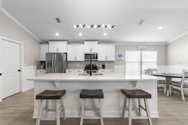 kitchen featuring appliances with stainless steel finishes, a large island, a sink, and visible vents