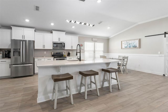 kitchen featuring lofted ceiling, a barn door, a sink, visible vents, and appliances with stainless steel finishes