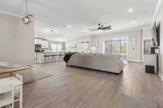 living room featuring a ceiling fan, light wood-type flooring, visible vents, and crown molding