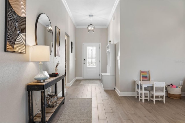 entryway with ornamental molding, an inviting chandelier, baseboards, and wood finished floors