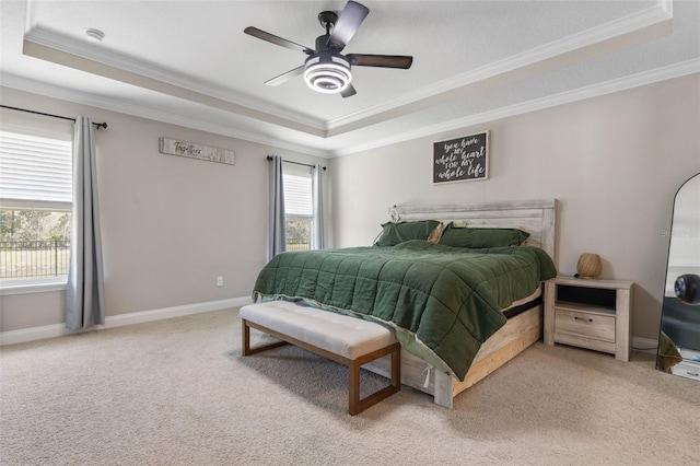 carpeted bedroom featuring multiple windows, baseboards, a raised ceiling, and ornamental molding