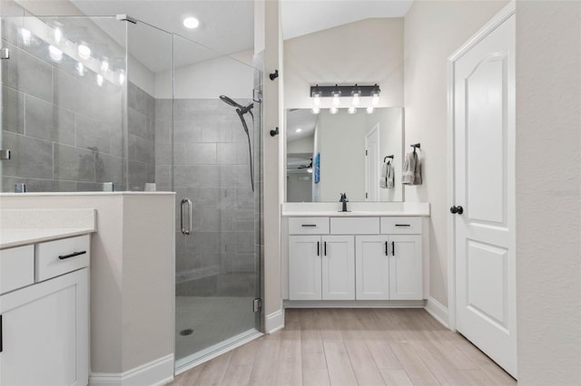 bathroom with lofted ceiling, a stall shower, wood finished floors, and vanity