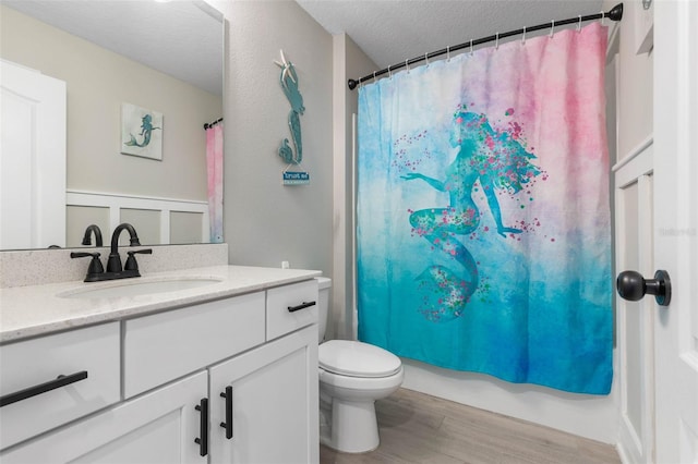 full bathroom featuring a textured ceiling, vanity, wood finished floors, and toilet