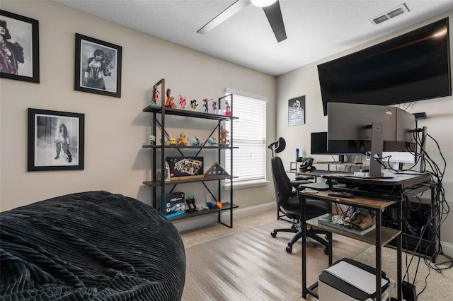 carpeted home office with a ceiling fan, visible vents, and baseboards