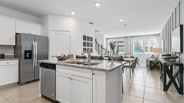 kitchen with open floor plan, stainless steel appliances, a sink, and white cabinets