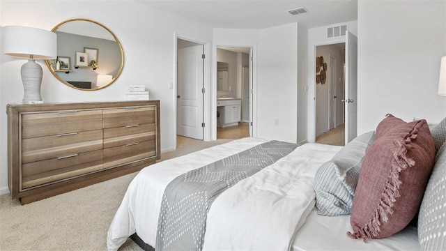 bedroom with light colored carpet, visible vents, and ensuite bathroom