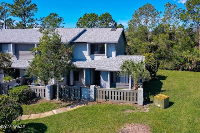 view of front of house with a fenced front yard, a front yard, and a shingled roof