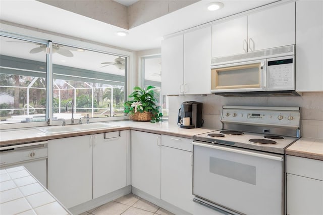 kitchen with white appliances, decorative backsplash, a sink, and white cabinets