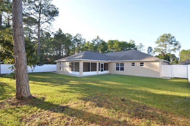 rear view of house with a fenced backyard, a lawn, and stucco siding