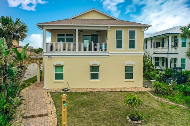 back of property with a yard, a balcony, and stucco siding