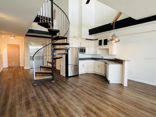 kitchen with white cabinets, dark countertops, dark wood-style floors, appliances with stainless steel finishes, and pendant lighting