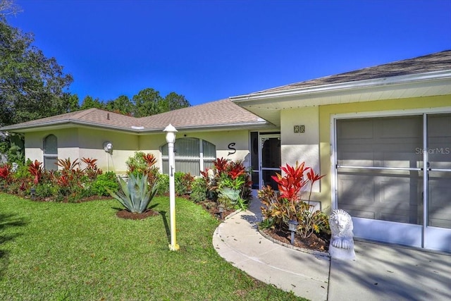 exterior space featuring a yard, a shingled roof, an attached garage, and stucco siding