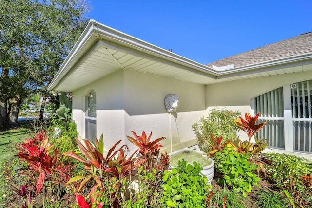 view of side of home with a shingled roof and stucco siding