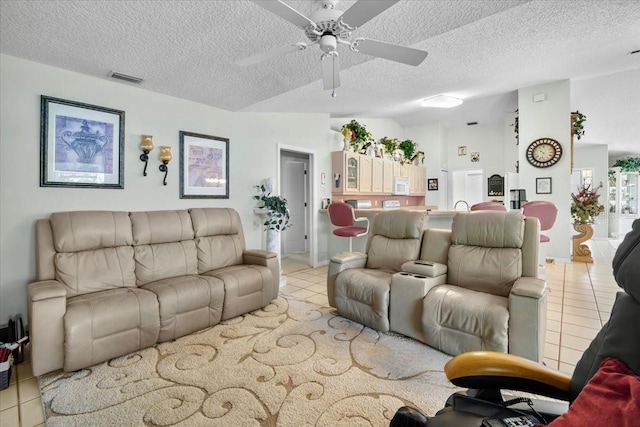 living room featuring light tile patterned floors, visible vents, vaulted ceiling, and a textured ceiling