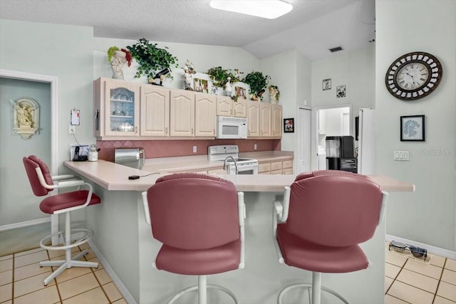 kitchen featuring light countertops, glass insert cabinets, white appliances, a peninsula, and a kitchen breakfast bar