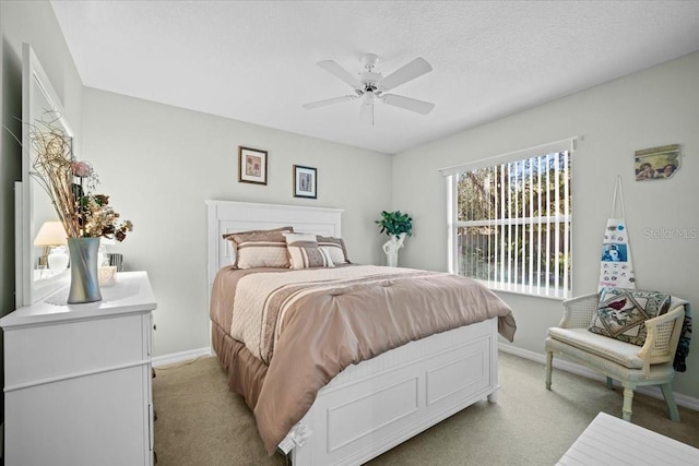 bedroom featuring light colored carpet, ceiling fan, a textured ceiling, and baseboards