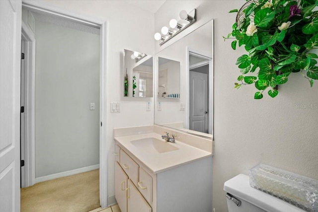 bathroom featuring toilet, vanity, and baseboards