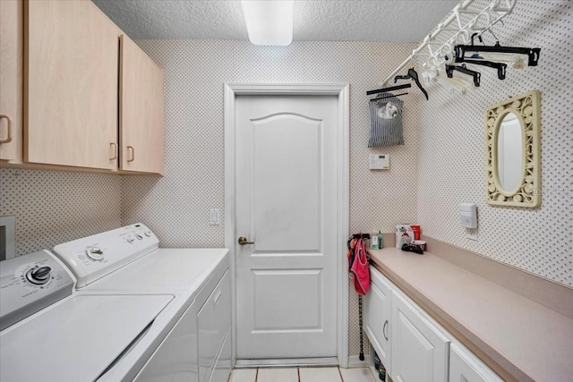 laundry room with cabinet space, light tile patterned floors, wallpapered walls, a textured ceiling, and separate washer and dryer