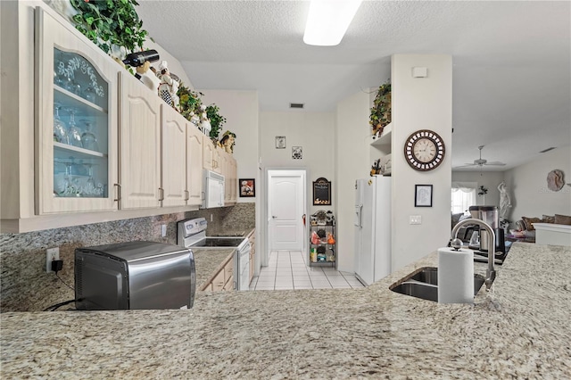 kitchen with white appliances, light stone counters, a sink, glass insert cabinets, and a ceiling fan