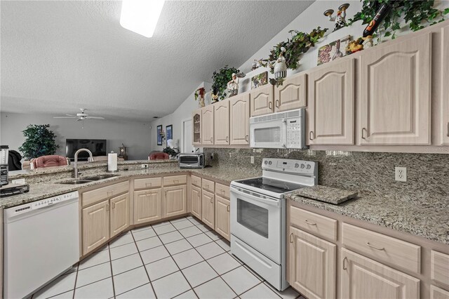 kitchen featuring white appliances, light brown cabinets, a sink, a textured ceiling, and lofted ceiling