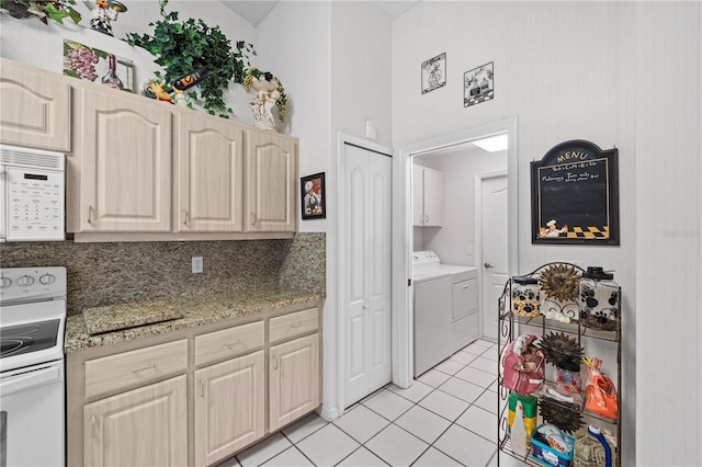 kitchen featuring white appliances, washing machine and clothes dryer, light tile patterned floors, and high vaulted ceiling