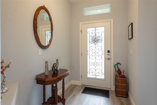 foyer with light wood-type flooring, a healthy amount of sunlight, and baseboards