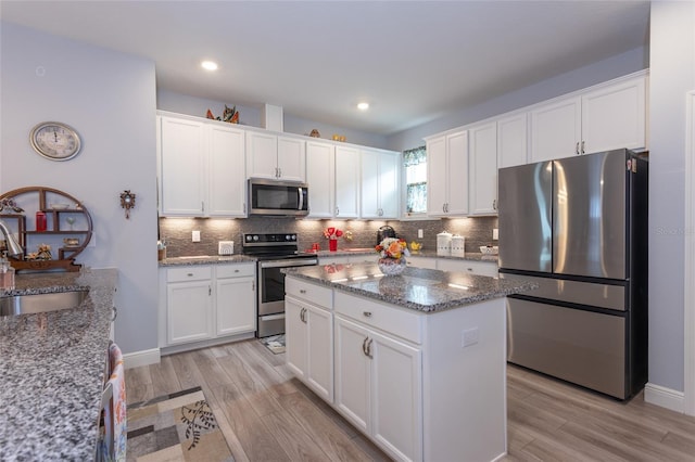 kitchen featuring stainless steel appliances, stone countertops, a sink, and white cabinetry