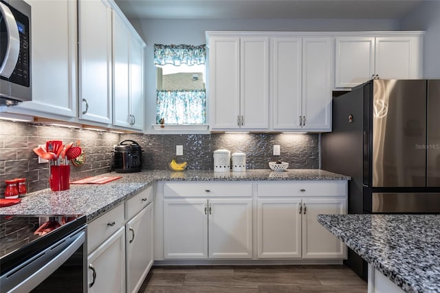 kitchen featuring light stone counters, appliances with stainless steel finishes, and white cabinetry