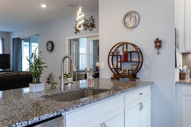 kitchen featuring a sink, visible vents, white cabinets, dishwasher, and dark stone countertops