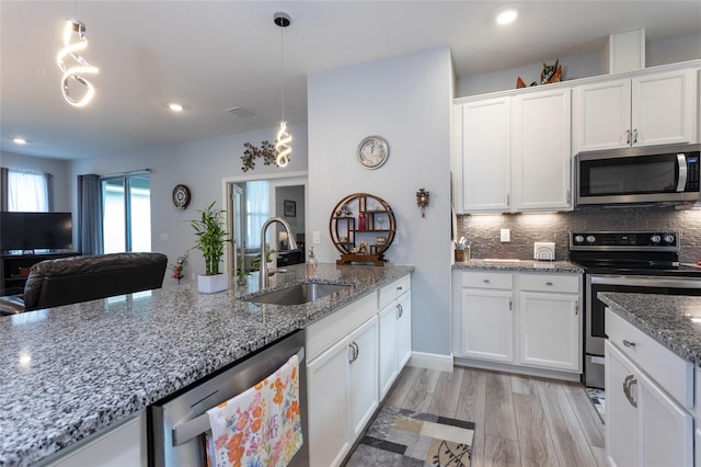 kitchen featuring appliances with stainless steel finishes, white cabinetry, and a sink