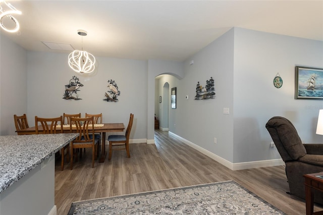 dining room featuring baseboards, arched walkways, a chandelier, and wood finished floors