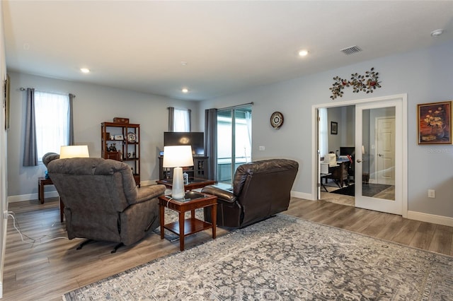 living area featuring plenty of natural light, wood finished floors, visible vents, and baseboards