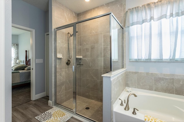 ensuite bathroom featuring wood finished floors, a shower stall, ensuite bath, and a bath