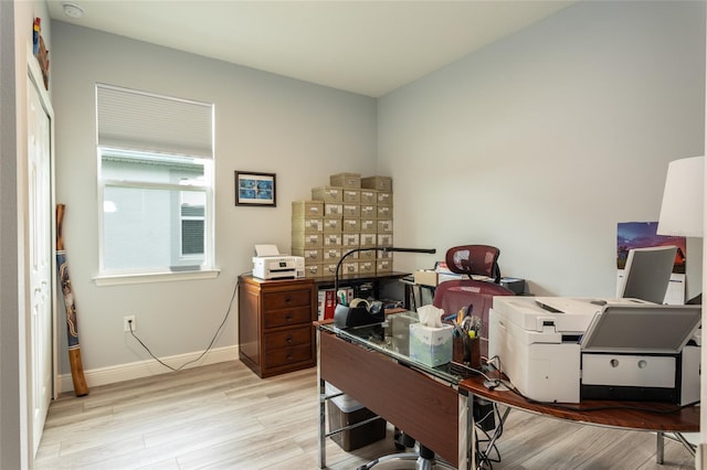 home office with light wood-style flooring and baseboards