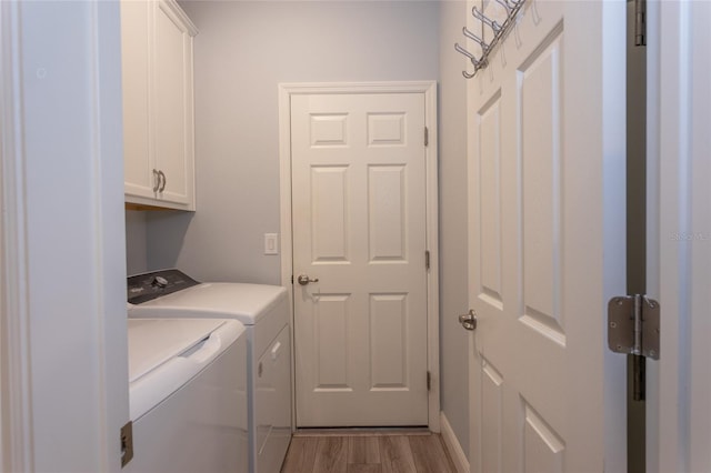 laundry room with light wood-style flooring, cabinet space, and washer and clothes dryer