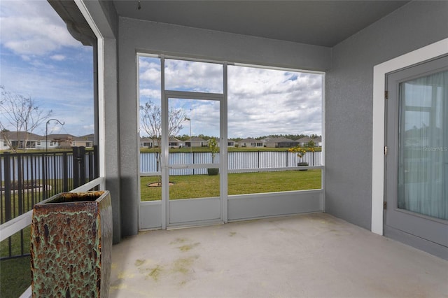 unfurnished sunroom featuring a water view and a residential view