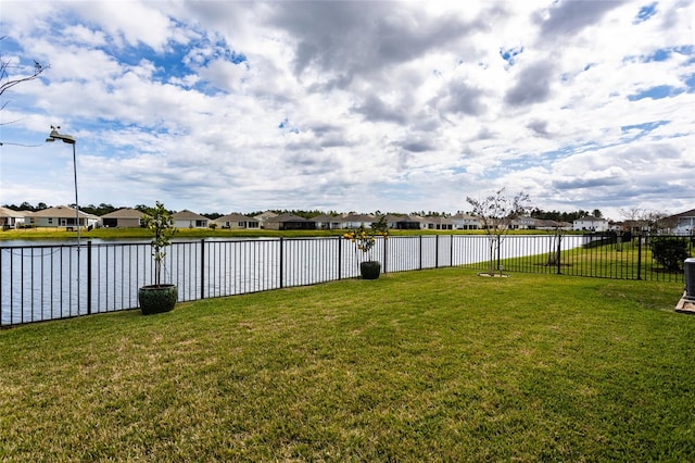 view of yard featuring a water view, fence, and a residential view