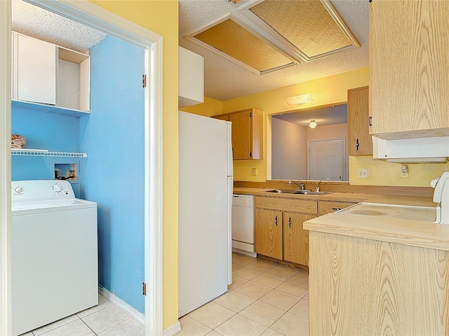 kitchen featuring light countertops, light tile patterned flooring, a sink, washer / dryer, and white appliances